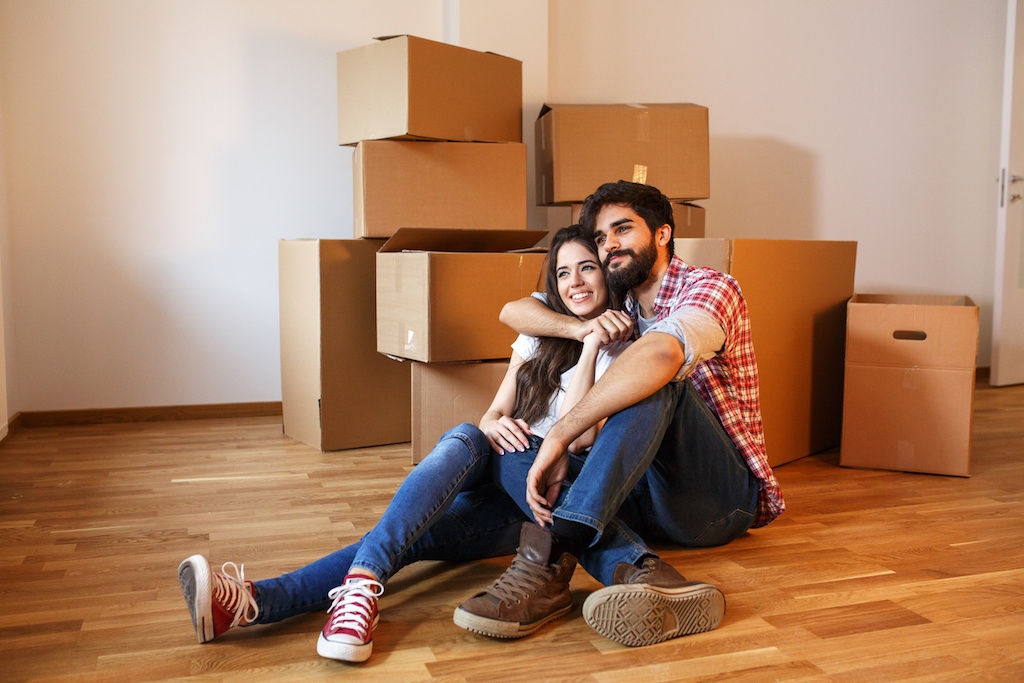 New apartment renters sitting on floor with boxes next to them